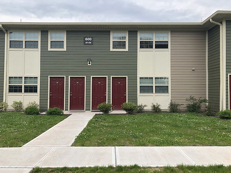 a building with three red doors and a grass yard